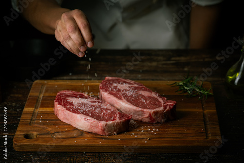 chef seasoning steak with salt and pepper