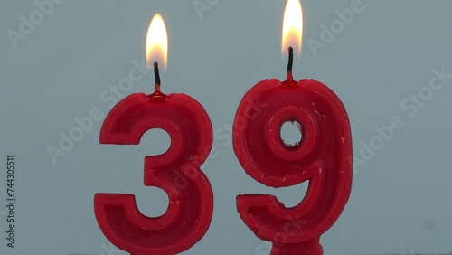 close up on timelapse melting a red number thirty ninth birthday candle on a white background.
 photo