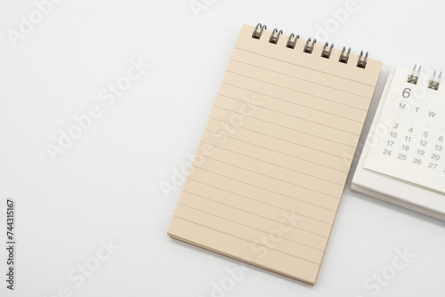 Empty Spiral notepad with brown lined papers and Simple desk calendar for JUNE in isolated background. Memo concept with copy space.
