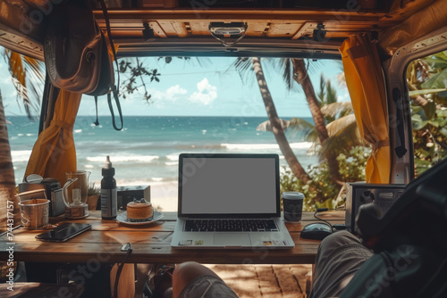 Digital Nomad concept: Closeup view of a van camper interior setting with a beautiful beach view background, focus on the laptop to evoke the idea of freedom from office and work while traveling... photo