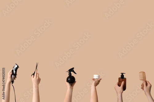 Many hands with different hairdressing supplies on beige background