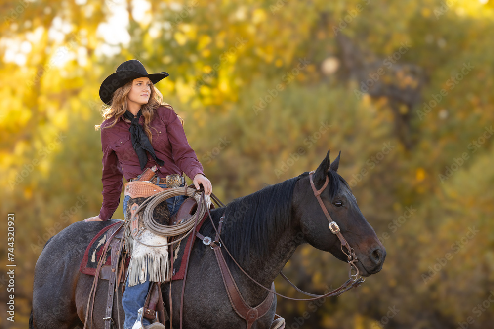 Obraz premium Pretty cowgirl sitting on horse wearing a cowboy hat and wildrag