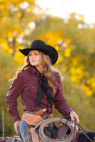 Pretty cowgirl sitting on horse wearing a cowboy hat and wildrag photo