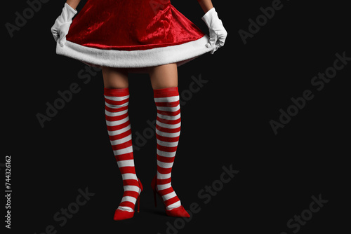 Young woman in Christmas stockings on dark background