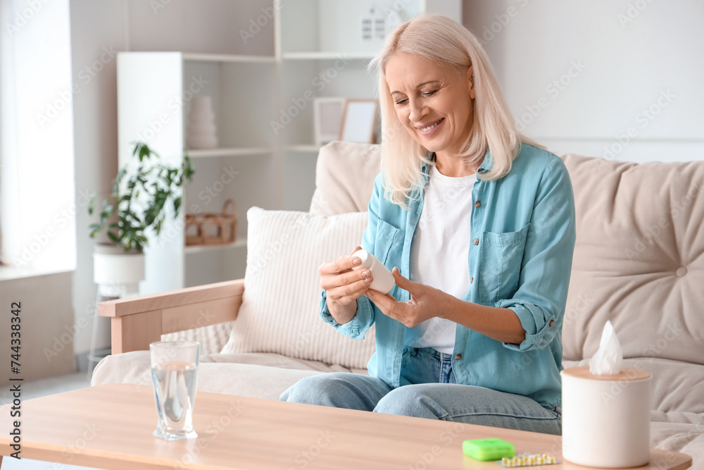 Mature woman holding bottle with pills at home Mature woman holding bottle with pills at home