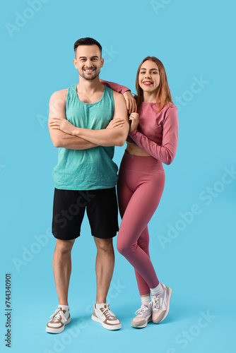 Beautiful young happy couple in sportswear on blue background