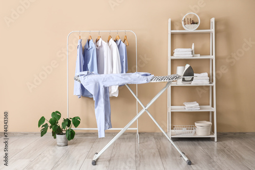 Interior of laundry room with rack, shelving unit and ironing board