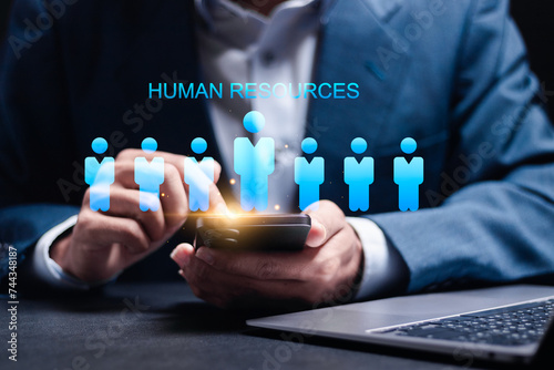 HR, Human Resources management concept. Recruitment, Employment, Headhunting, Team building. Businessman use smartphone and laptop with HR icon on virtual screen. photo
