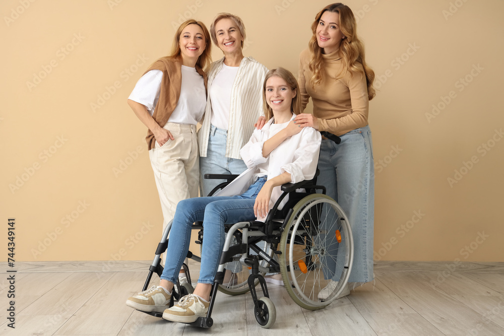 Group of people with young woman in wheelchair near beige wall