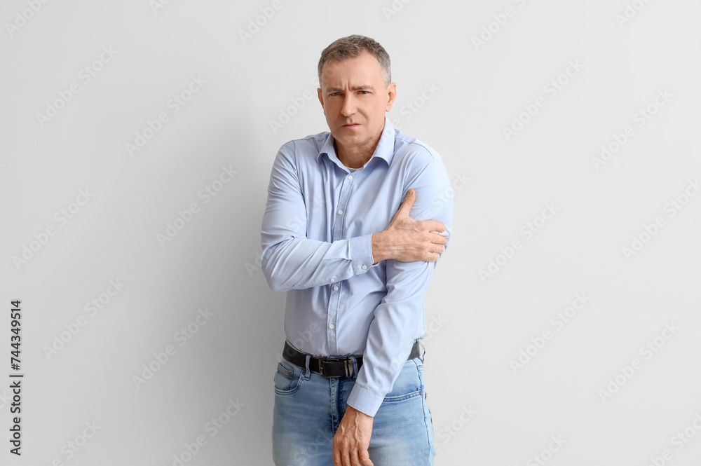 Mature man suffering from shoulder pain on light background Mature man suffering from shoulder pain on light background