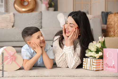 Cute little boy and his mother with gifts, tulips and greeting card at home. International Women's Day