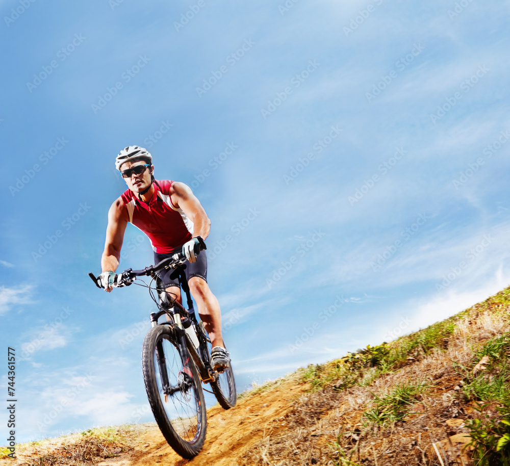 Nature, fitness and man athlete with bicycle in park for marathon, race or competition training. Blue sky, sports and male cyclist riding bike for cardio workout or exercise in outdoor forest.