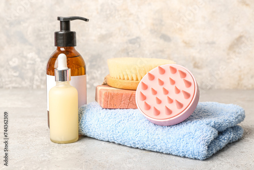 Hair scalp massager with shampoo bar and bottles of cosmetic products on grunge grey background