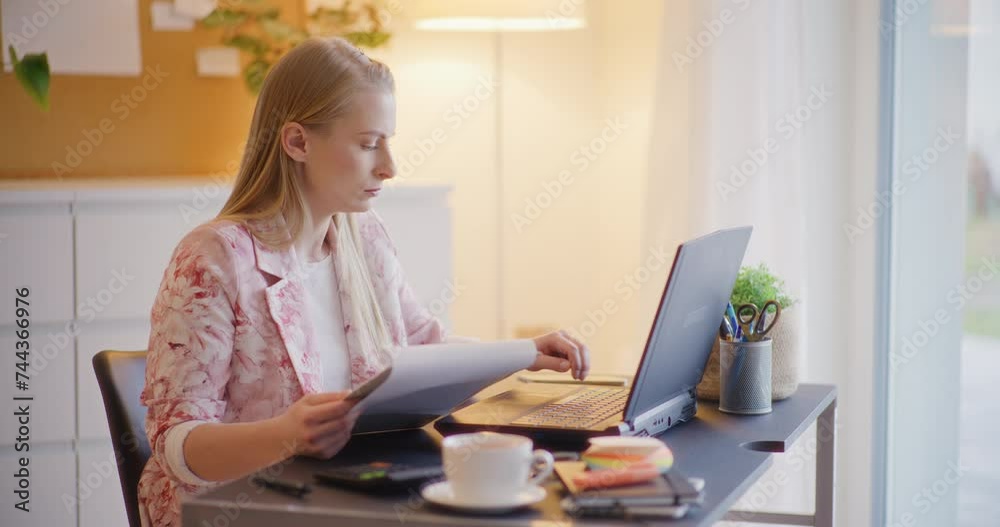 Entrepreneur examining document while using laptop Entrepreneur examining document while using laptop