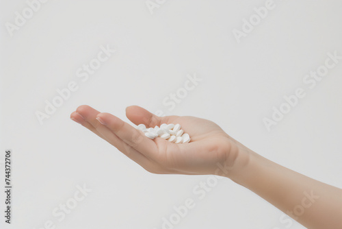 Woman hand with pills in hand taking pills on white background.