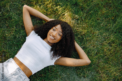 Female african student posing looking at camera lying on a grass