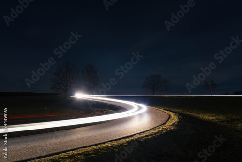 Fototapeta Naklejka Na Ścianę i Meble -  Light trails from car riding in curve asphalt street at night. Transportation background, long exposure