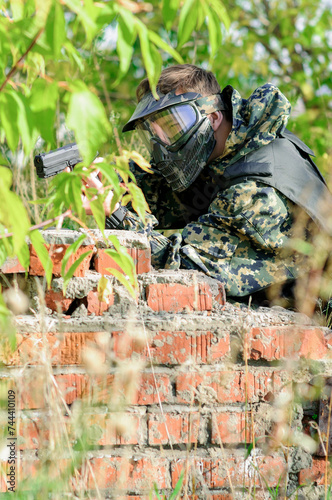 military man with a pistol in his hands, in camouflage uniform, protective mask and goggles