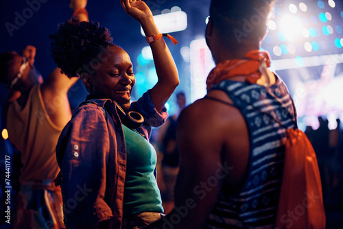 Happy black woman dancing with her boyfriend during open air music concert at night.