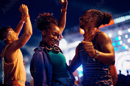 Black carefree couple dancing and having fun on summer music festival at night. photo