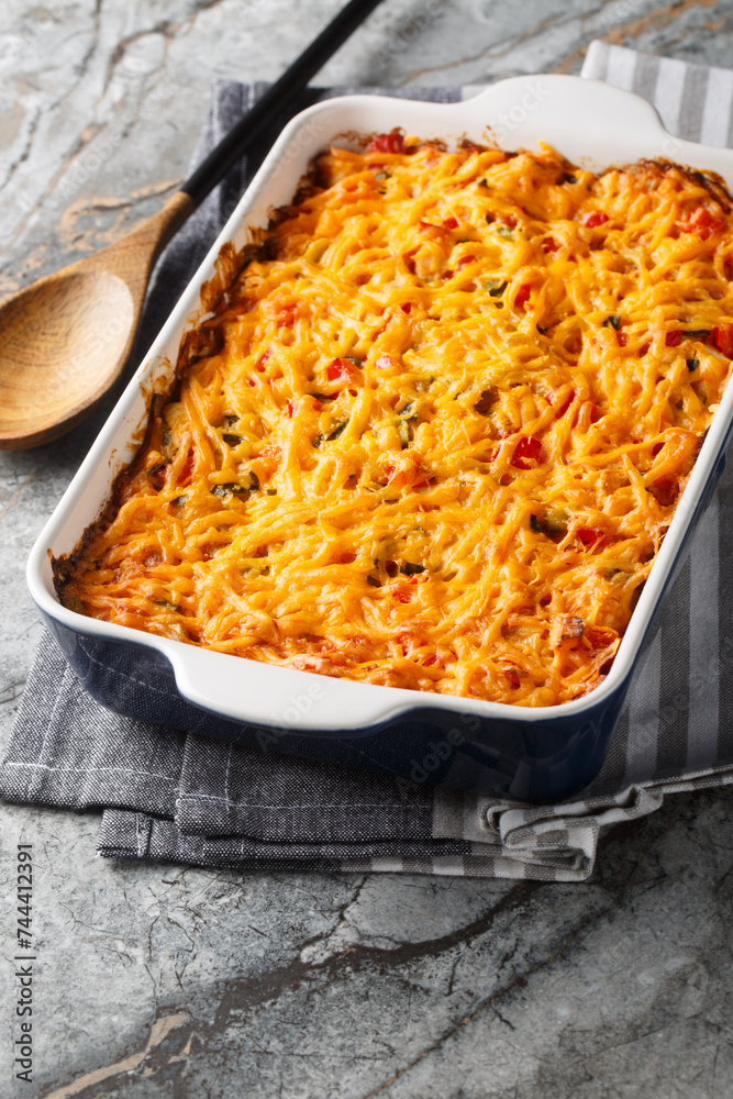 King Ranch Chicken Casserole with pulled chicken, corn tortillas, shredded cheese, peppers, and spicy green chiles close-up in a baking dish on a marble table. Vertical King Ranch Chicken Casserole with pulled chicken, corn tortillas, shredded cheese, peppers, and spicy green chiles close-up in a baking dish on a marble table. Vertical