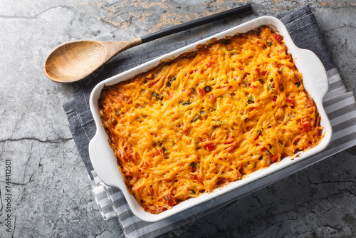 King Ranch Casserole is classic Texas comfort food with vegetables, cheddar cheese, tortilla and cream close-up in a baking dish on a marble table. Horizontal top view from above