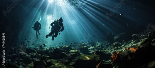 divers pass through a cave at the bottom of the deep sea photo