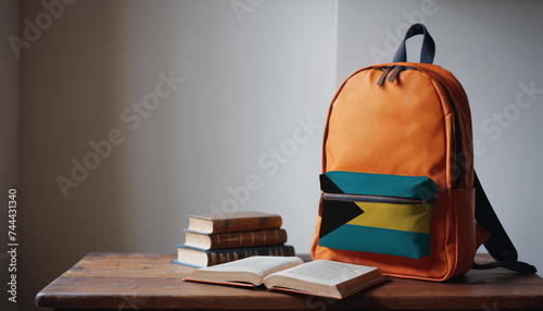 Back to school and happy time! Pile of books and backpack with Bahamas flag on the desk at the elementary school.