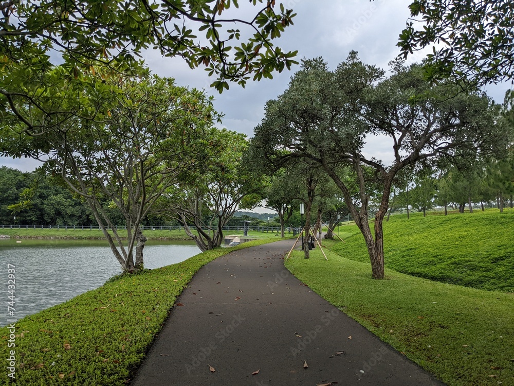 Mini jogging park on the Semarang Central Java with lake, cloudy vibes and blue sky. The photo is suitable for park background, relax and enjoy place content media.