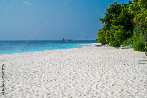 Fototapeta Naklejka Na Ścianę i Meble -  Beautiful sandy beach with a dense green forest. Seaplane floats on the sea.