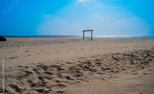 Fototapeta Naklejka Na Ścianę i Meble -  Double wooden swing on the sandy beach with an ocean view. Sunny weather.