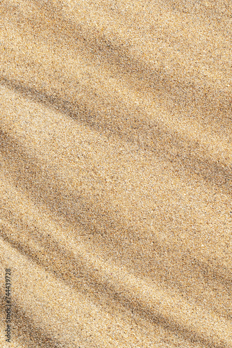 Vertical wavy sand texture close-up. Sandy beach background. Summer, vacation, relax backdrop, top view.