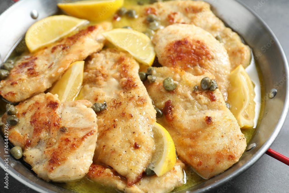 Delicious chicken piccata with lemons on grey table, closeup