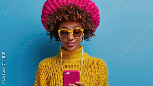 A stylish and carefree woman is enjoying music through headphones on her smar...