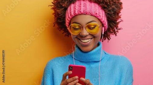 A stylish, carefree woman enjoys music through headphones on her smartphone, ...