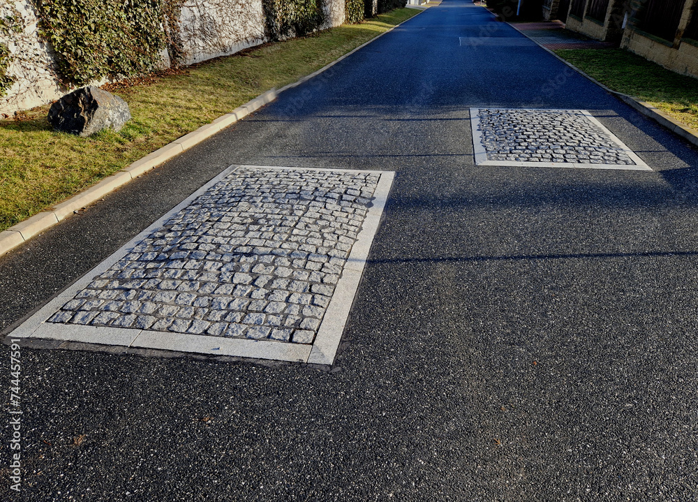 Fototapeta premium in the middle of the road leading to the residential area, the police and the traffic office installed a red plastic retarder. raised square made of rubber beveled on the sides, arrow, triagle