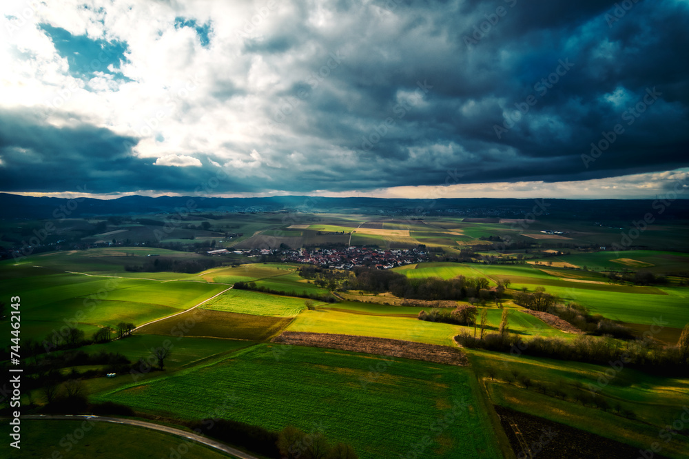 Aerial view of green fields under a dramatic cloudy sky