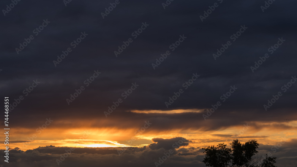 Dramatic yellow sunset with vibrant clouds lit by a sun