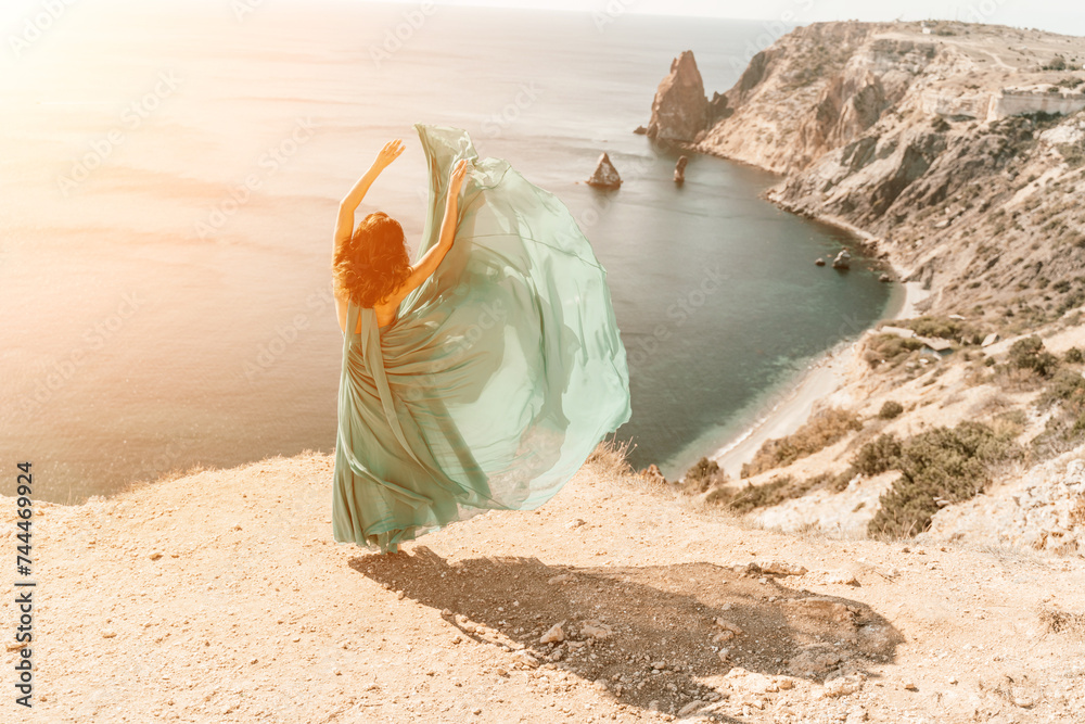 Woman green dress sea. Female dancer posing on a rocky outcrop high above the sea. Girl on the nature on blue sky background. Fashion photo. Woman green dress sea. Female dancer posing on a rocky outcrop high above the sea. Girl on the nature on blue sky background. Fashion photo.
