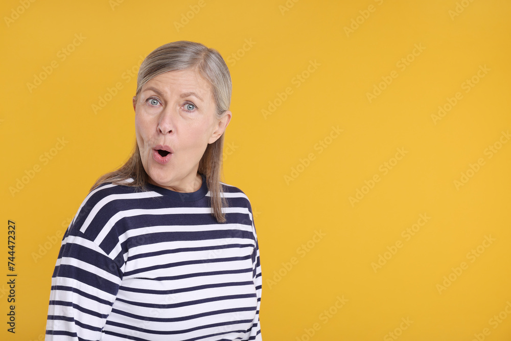 Portrait of surprised senior woman on yellow background, space for text Portrait of surprised senior woman on yellow background, space for text