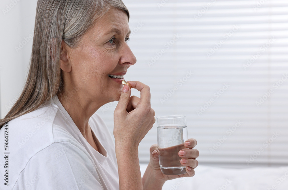 Beautiful woman taking vitamin pill at home Beautiful woman taking vitamin pill at home