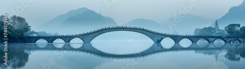 Sweeping Arch Bridge Over Tranquil Lake in Misty Mountain Setting