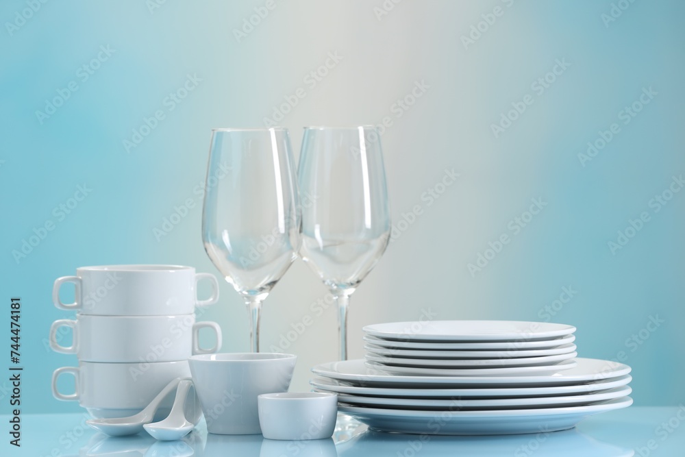 Set of many clean dishware and glasses on light blue table Set of many clean dishware and glasses on light blue table