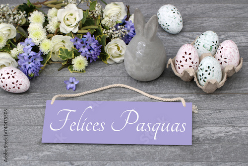 El texto Felices Pascuas escrito en un cartel con adornos y flores de Pascua.