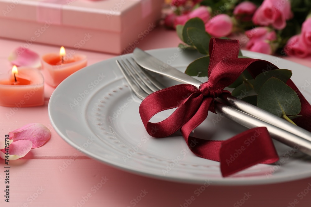 Place setting with roses and candles on pink wooden table, closeup. Romantic dinner Place setting with roses and candles on pink wooden table, closeup. Romantic dinner