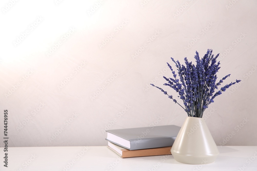 Bouquet of beautiful preserved lavender flowers and notebooks on white table near beige wall, space for text Bouquet of beautiful preserved lavender flowers and notebooks on white table near beige wall, space for text
