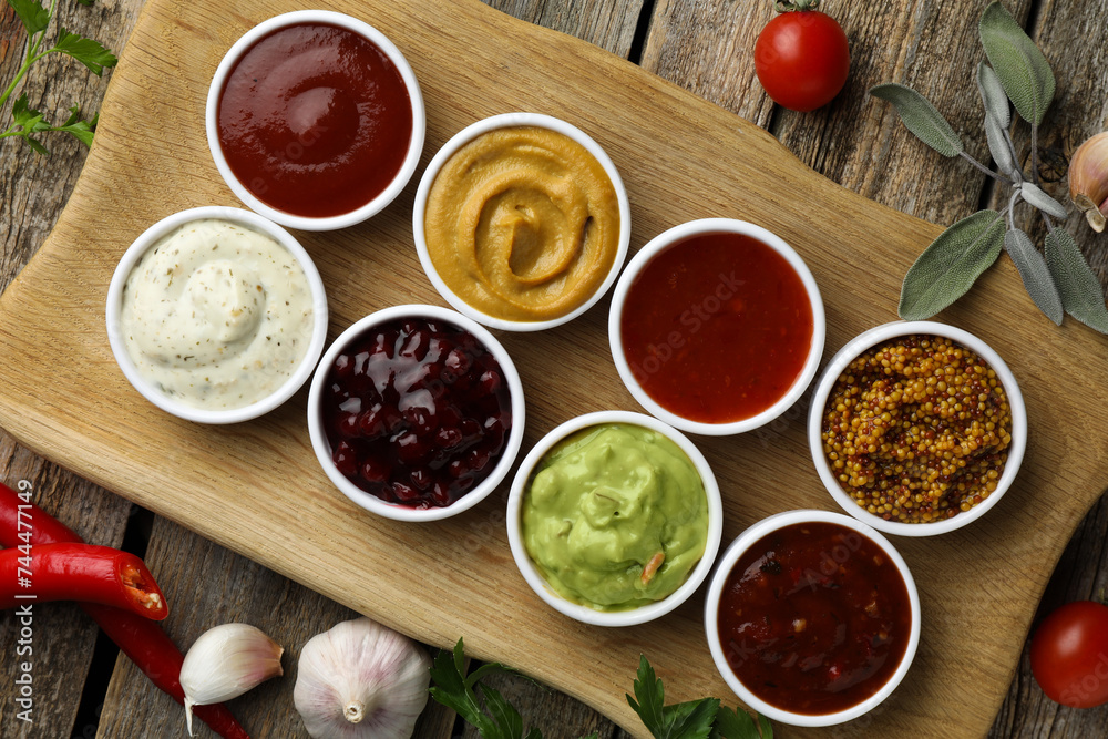 Different tasty sauces in bowls and ingredients on wooden table, top view Different tasty sauces in bowls and ingredients on wooden table, top view