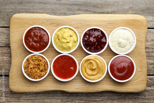 Different tasty sauces in bowls on wooden table, top view