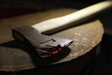 Axe with blood on rusty metal surface, closeup