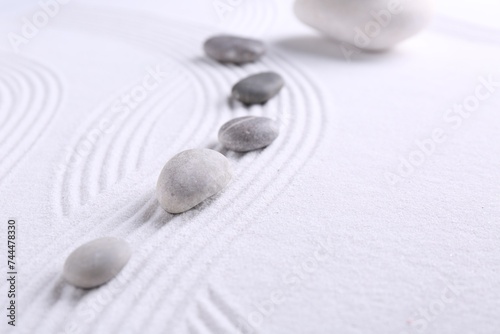 Zen garden stones on white sand with pattern, space for text